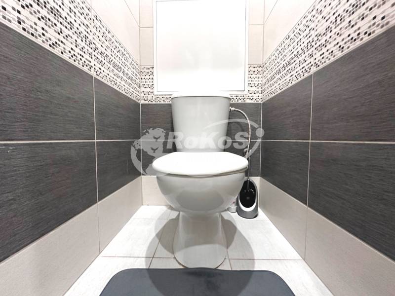 Toilette mit Keramikfliesen in einer 2-Zimmer-Wohnung, in Schwarz-Weiß-Tönen.