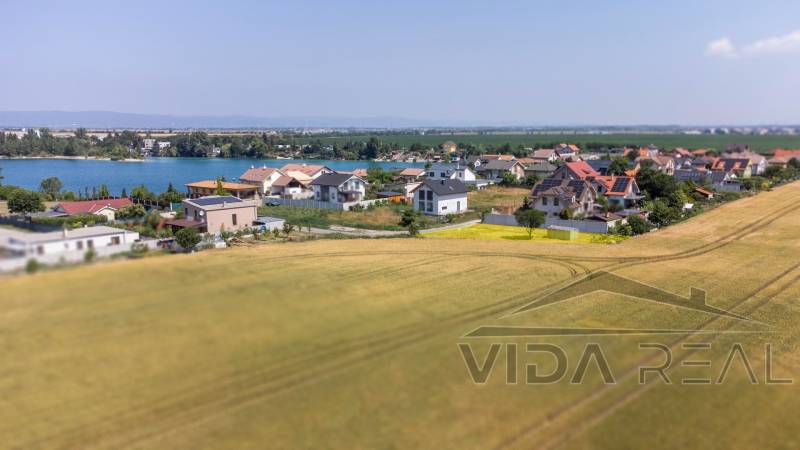 Grundstücke - Wohnen in Dunajská Lužná mit Blick auf den See, Häuser und Felder.