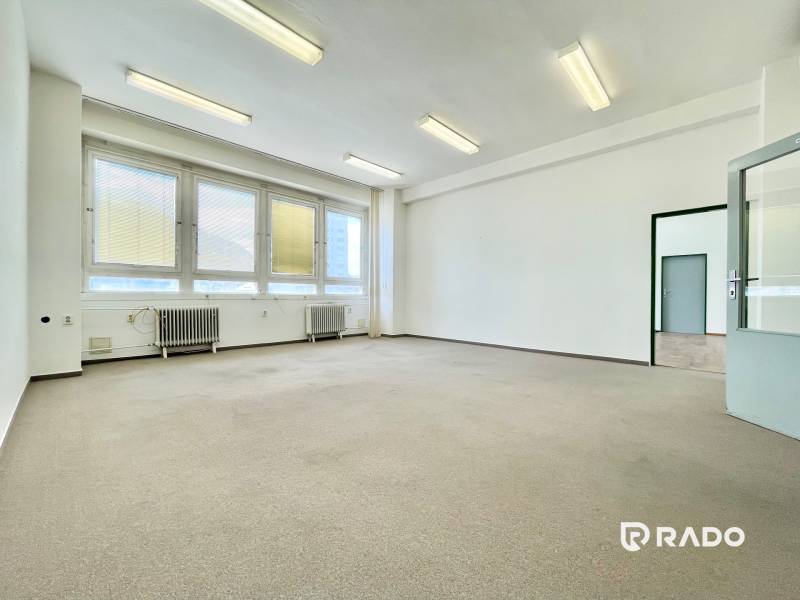 Ein hell erleuchteter Raum in einem Büro mit großen Fenstern und Heizkörpern.