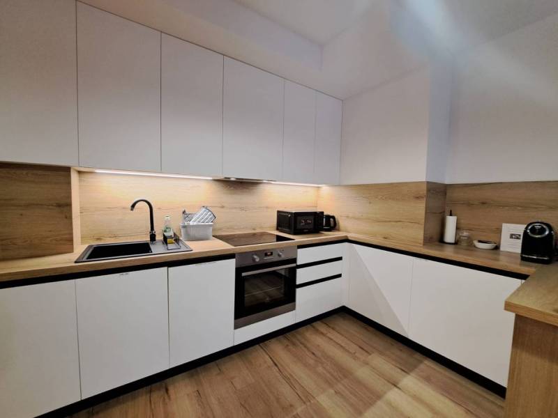 Küchenzeile in einer 2-Zimmer-Wohnung mit weißen Schränken und einer Holzarbeitsplatte.