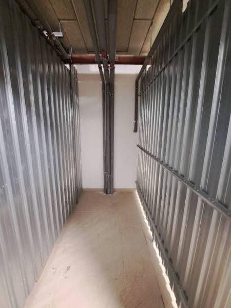 Stauraum in einer 2-Zimmer-Wohnung mit Metallwänden und Rohren.