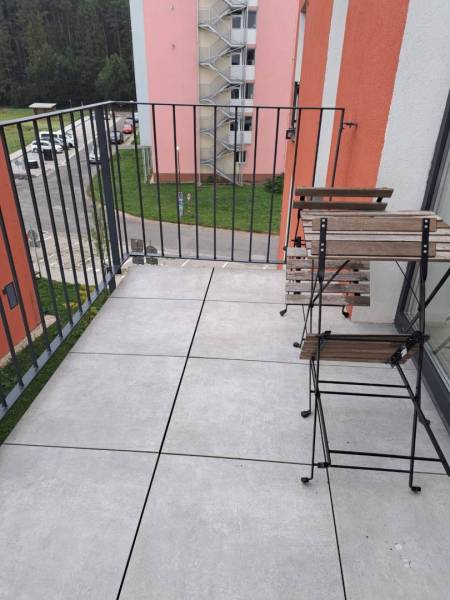 Ein Balkon mit Blick auf die Jilemnického-Straße in der Stadt Svit; enthält Holzmöbel.