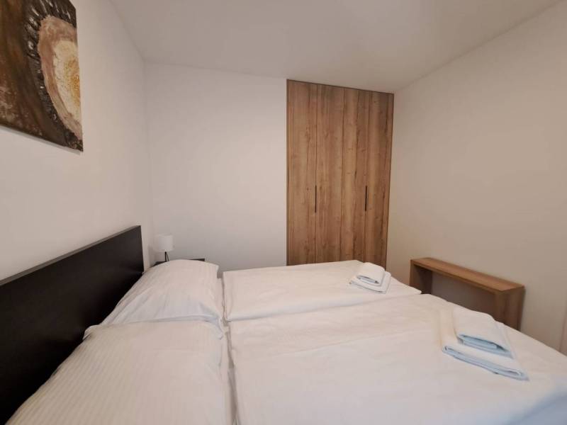 Schlafzimmer in einer 2-Zimmer-Wohnung mit Bett, Holzschrank und Bild an der Wand.
