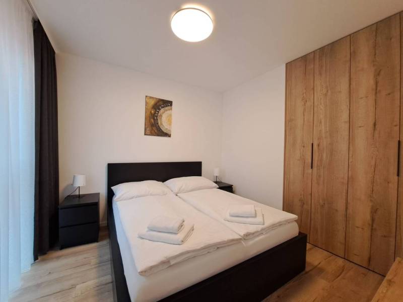 Schlafzimmer mit Doppelbett, Tischen und Schrank in einer Zweizimmerwohnung.