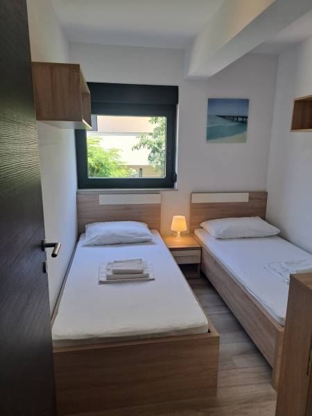 Ein Zimmer in einer 3-Zimmer-Wohnung mit zwei Betten, einem Nachttisch und einem Fenster mit Aussicht.