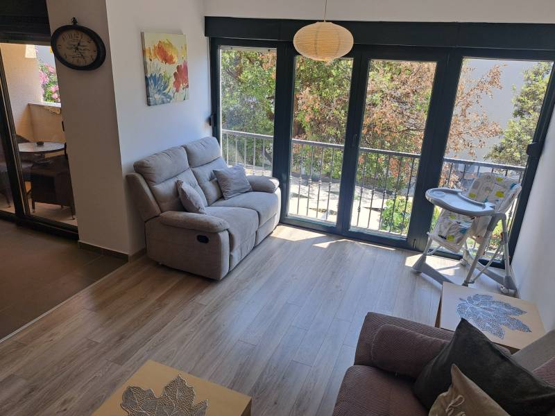 Wohnzimmer einer 3-Zimmer-Wohnung mit Sofa, Balkon und Hochstuhl für Kleinkinder.