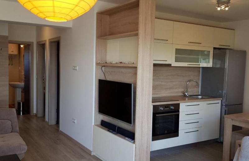 Küche in einer 3-Zimmer-Wohnung mit eingebauten Geräten und einem Fernseher an der Wand.