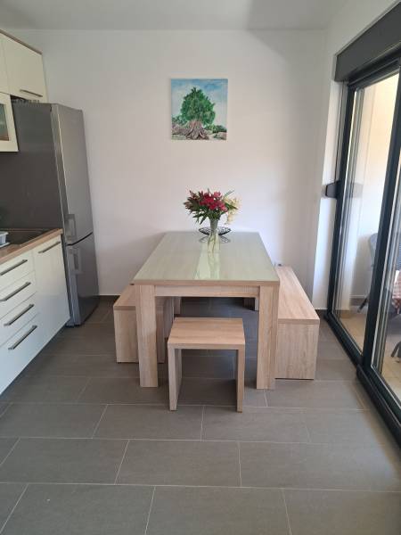 Essbereich in einer 3-Zimmer-Wohnung mit einem Holztisch, Blumen und einem Baumgemälde an der Wand.
