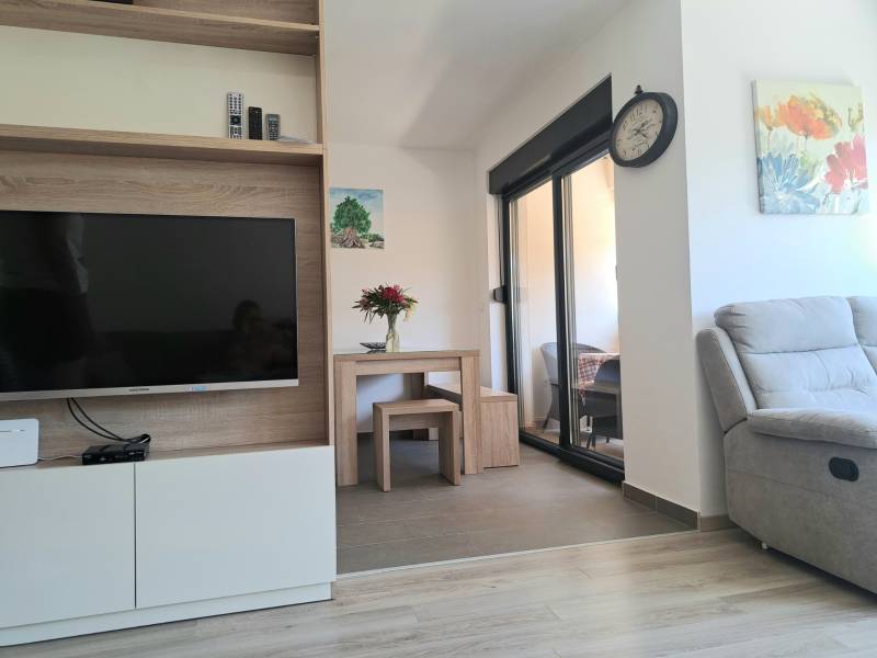 Wohnzimmer in einer 3-Zimmer-Wohnung mit Fernseher und bequemen Sessel.
