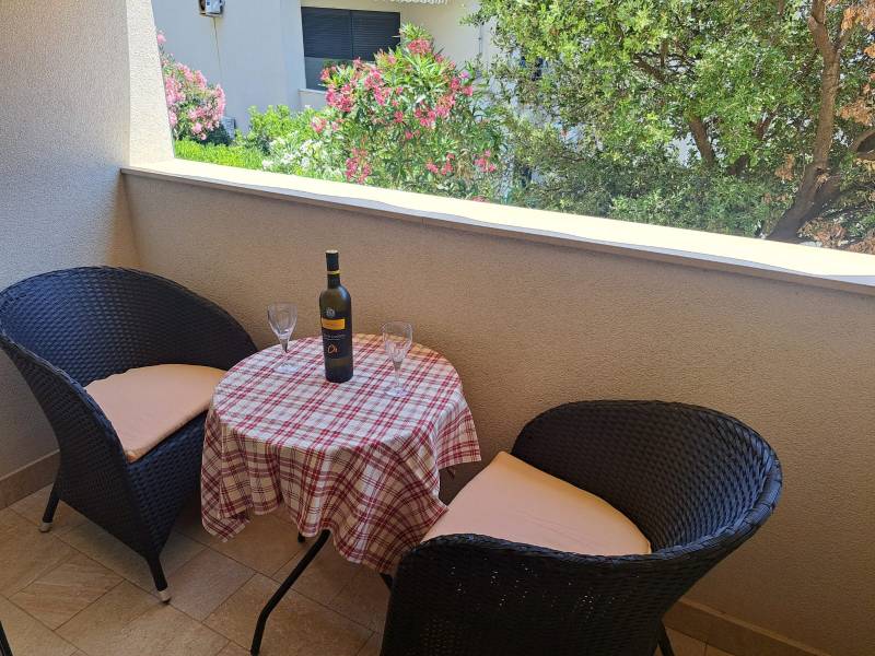 Der Balkon einer 3-Zimmer-Wohnung mit zwei Stühlen und einem Tisch mit Wein und Gläsern.