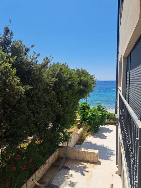 Blick aus einer 3-Zimmer-Wohnung in Mandre auf das Meer, gesäumt von Grün und Fliesen.
