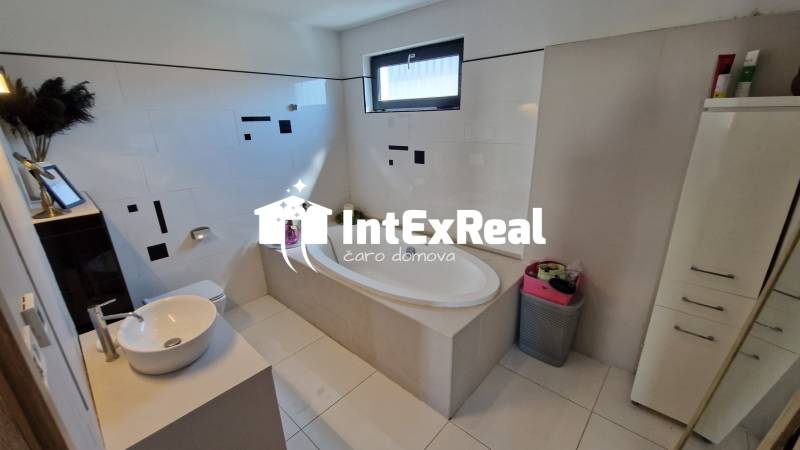 Badezimmer in einem Einfamilienhaus mit Badewanne, Waschbecken und Stauraum.