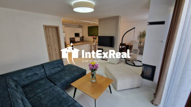Wohnzimmer in einem Einfamilienhaus mit komfortabler Sitzgelegenheit und moderner Küche.