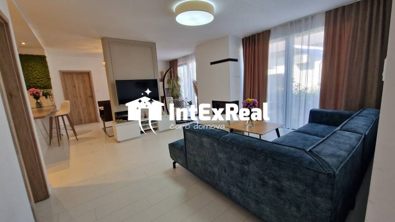 Innenraum eines Einfamilienhauses mit Sofa, Fernseher und Esstisch.