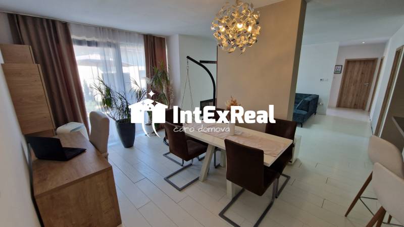 Esszimmer in einem Einfamilienhaus mit großem Tisch, Stühlen, Vorhängen und Kronleuchter.
