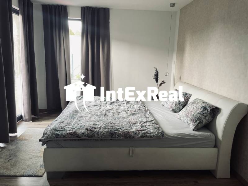 Schlafzimmer im Einfamilienhaus mit Bett, Vorhängen und Teppich, helle Zimmer.