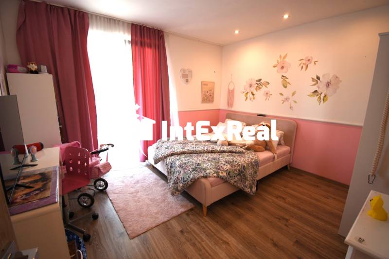 Kinderzimmer in einem Einfamilienhaus mit rosa Vorhängen und Blumendekoration an der Wand.