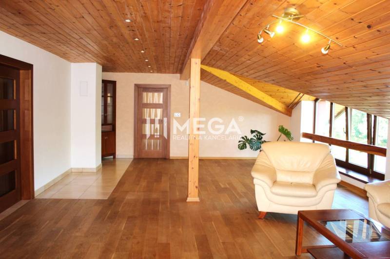 Dachgeschosswohnung mit 3 Zimmern, Holzelementen, Ledersofas und großen Fenstern.