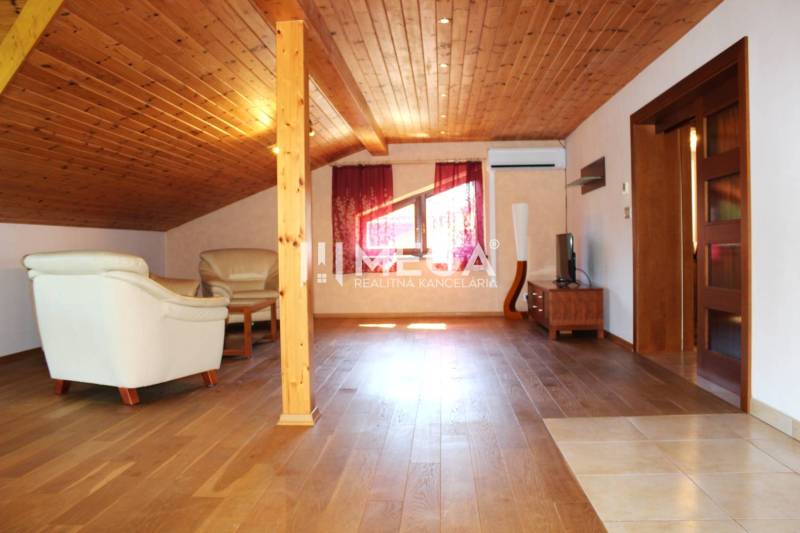 Dachgeschosswohnung mit Holzbalkendecke und Ledersitzmöbeln in einer 3-Zimmer-Wohnung.