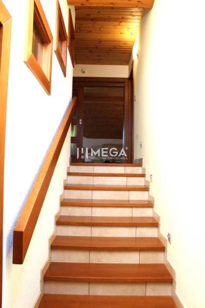 Eine Treppe mit einem Holzgeländer in einer 3-Zimmer-Wohnung, Blick auf die Holzdecke.