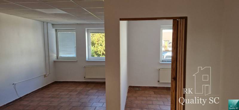 Das Innere des Gebäudes mit weißen Wänden, braunen Fliesen und drei Fenstern mit Ausblick.