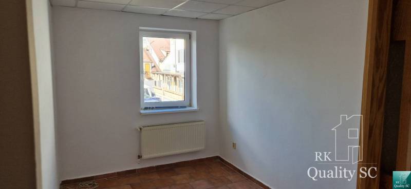 Ein Zimmer mit einem Fenster, einem Heizkörper und weißen Wänden in einem Gebäude.