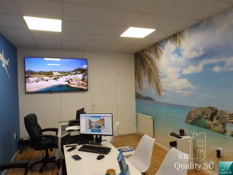 Ein Büro mit einem Computer und einer Dekoration mit einem tropischen Strand an der Wand in einem Gebäude.