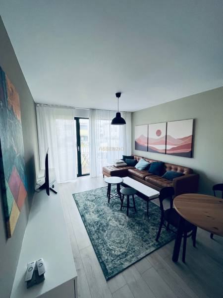 Wohnzimmer in einer 2-Zimmer-Wohnung mit Ledersofa, rundem Tisch und dekorativen Bildern.