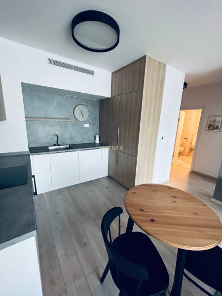 Küche in einer 2-Zimmer-Wohnung mit Holztisch und schwarzen Stühlen.