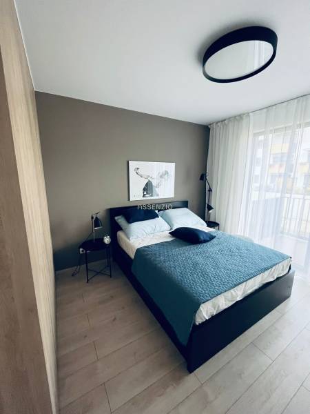 Schlafzimmer in einer 2-Zimmer-Wohnung mit Bett, Nachttischen und einem Bild an der Wand.