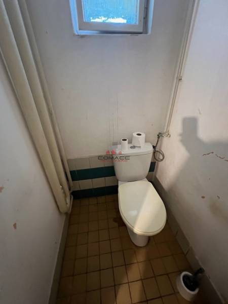 Badezimmer mit Toilette in einem Einfamilienhaus, enthält ein Fenster, Fliesen und Toilettenartikel.