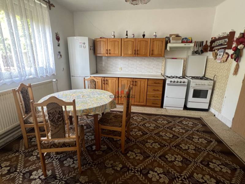 Küche in einem Einfamilienhaus mit Esstisch, Holzschränken und Gasherd.