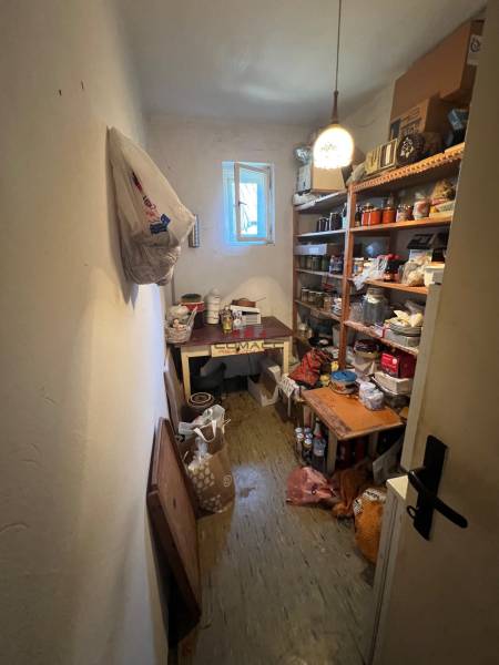 Lagerraum in einem Einfamilienhaus mit Regalen voller verschiedener Gegenstände und offenem Fenster.