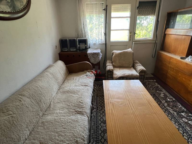 Wohnzimmer in einem Einfamilienhaus mit Sofa, Sessel und Holzmöbeln.