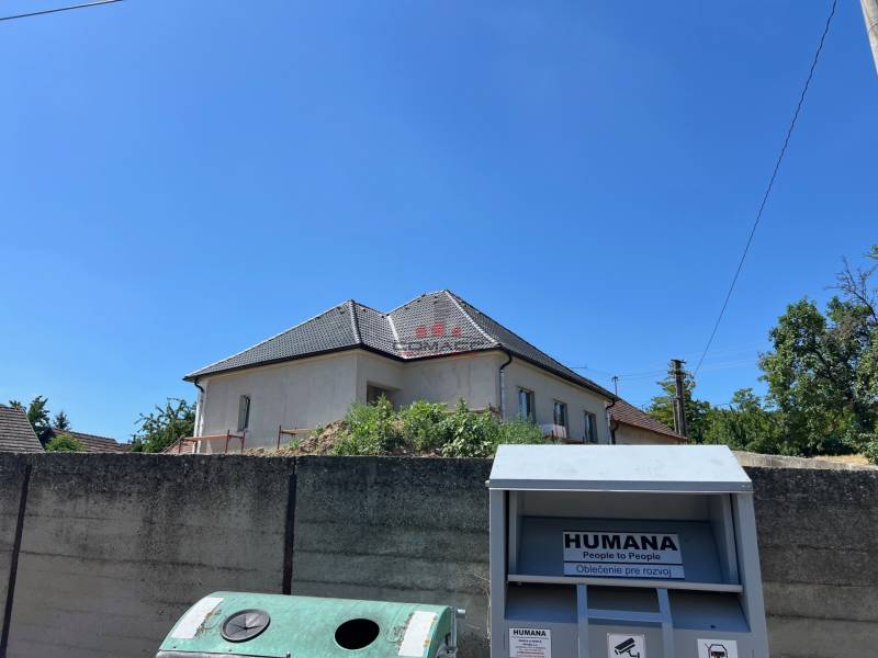 Ein Einfamilienhaus in Sasinkovo in der Straße Sasinkovo hinter einem Betonzaun mit blauem Himmel.