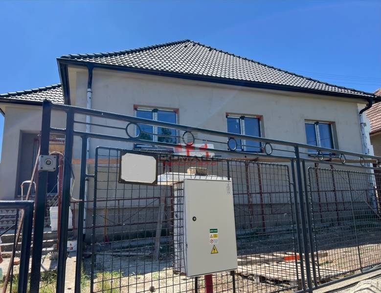 Ein Einfamilienhaus in Sasinkovo in der Sasinkovo-Straße mit unvollendeter Fassade hinter einem Metallzaun.