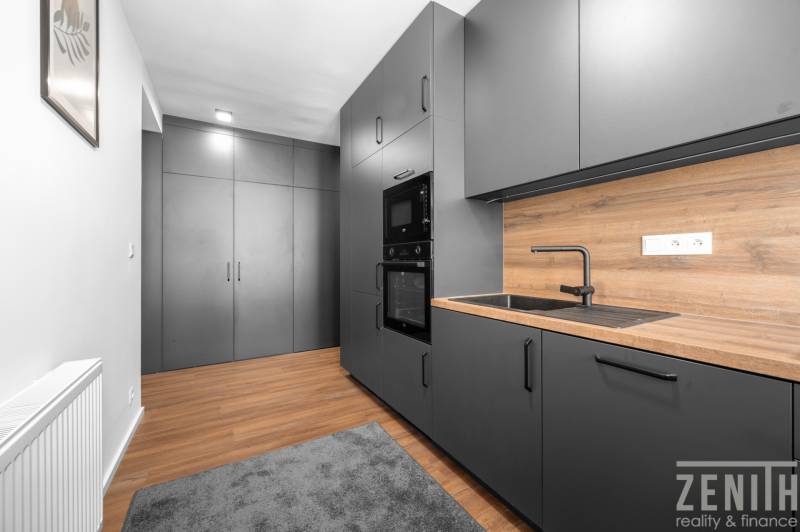 Küche mit schwarzen Schränken und einer Arbeitsplatte aus Holz in einer 3-Zimmer-Wohnung.