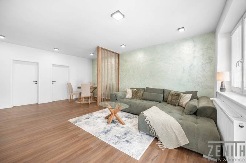 Wohnzimmer in einer 3-Zimmer-Wohnung mit Sofa, Esstisch und Holzboden.