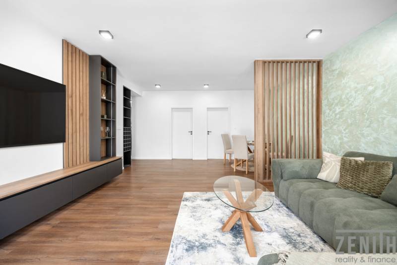 Wohnzimmer mit einem Teppich und einem grünen Sofa in einer 3-Zimmer-Wohnung.