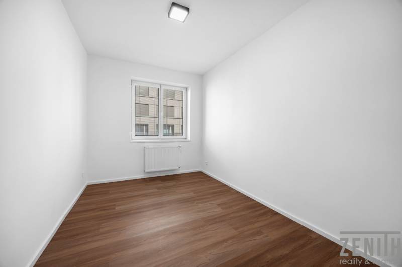 Ein leerer Raum mit Holzboden und einem Fenster in einer 3-Zimmer-Wohnung.