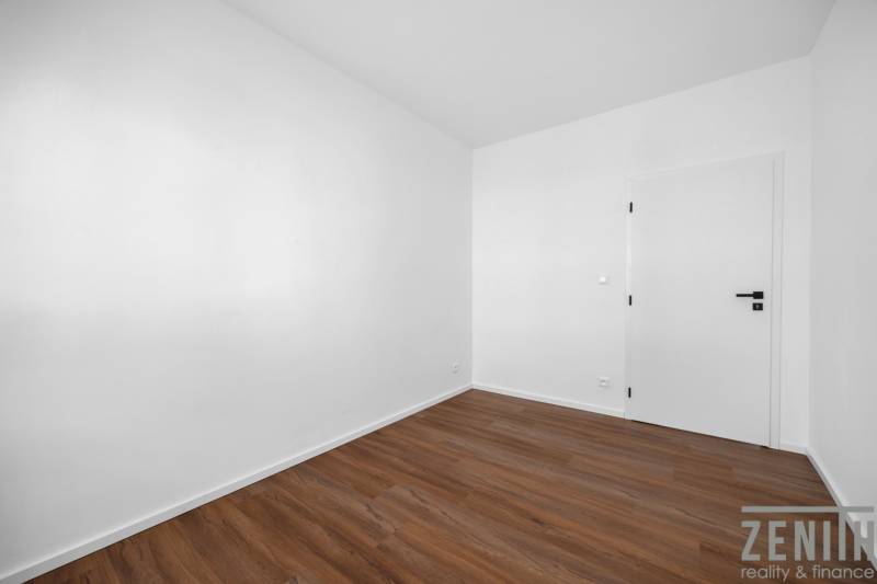 Ein leerer Raum mit Holzboden und weißen Wänden in einer 3-Zimmer-Wohnung.