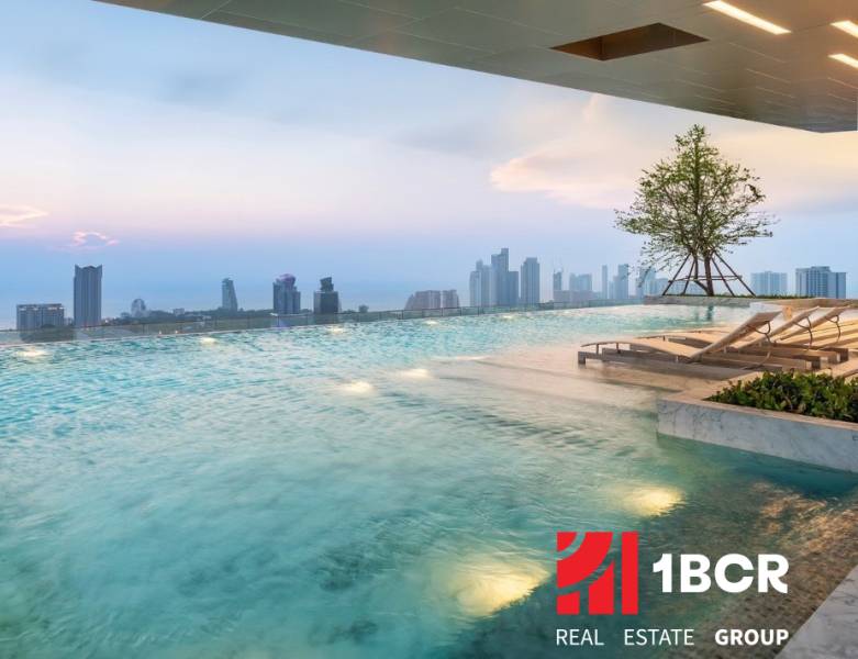 Ein Pool mit Liegestühlen und Blick auf die Skyline von Pattaya, Wohnungsbau.