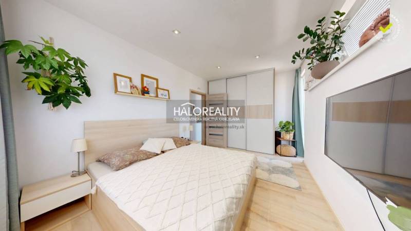 Schlafzimmer in einer 3-Zimmer-Wohnung mit Bett, Schrank, Bildern und grünen Pflanzen.