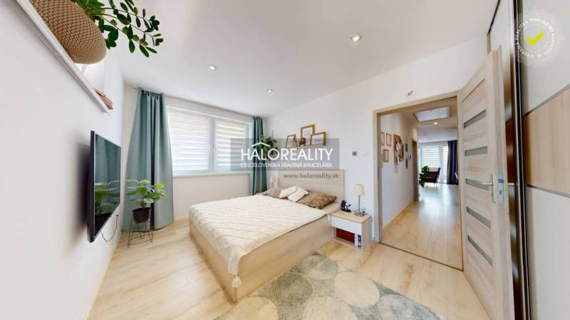 Schlafzimmer in einer 3-Zimmer-Wohnung mit Bett, Fernseher und Pflanzen, hellem Interieur.