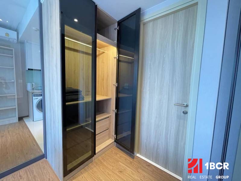 Ein Kleiderschrank mit offenen Türen in einer Zweizimmerwohnung, neben dem Küchenbereich.