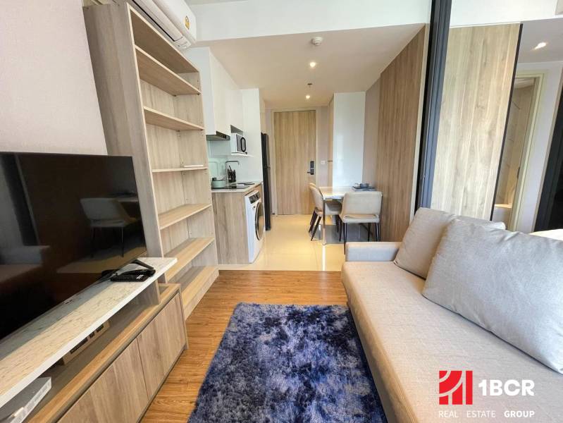 Wohnzimmer in einer Zweizimmerwohnung mit Sofa, Fernseher und Essecke.