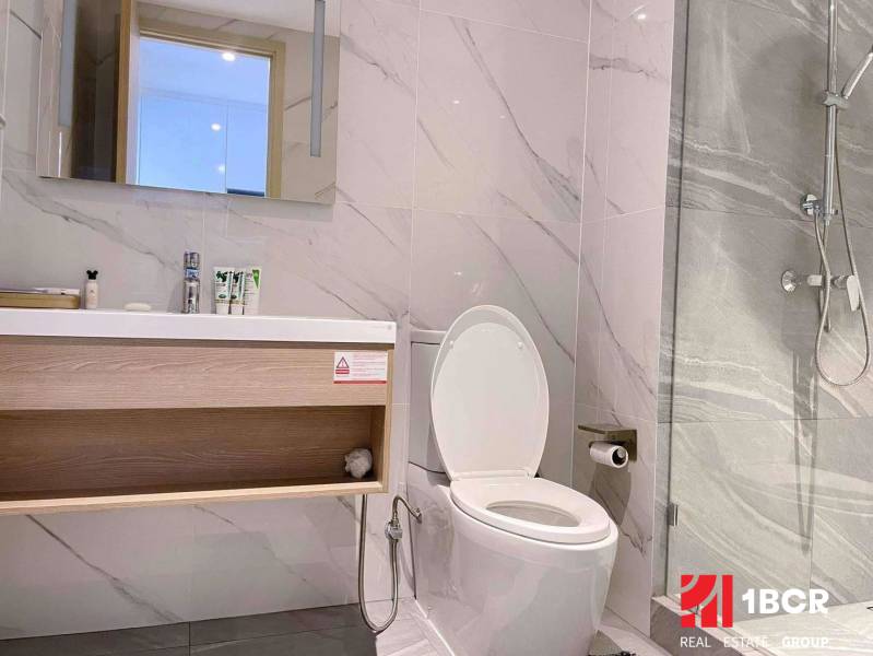 Badezimmer in einer 2-Zimmer-Wohnung mit weißen Wänden, Spiegel und Dusche.