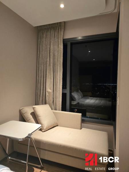 Ein Sofa und ein Tisch in einer Einzimmerwohnung mit nächtlichem Ausblick.