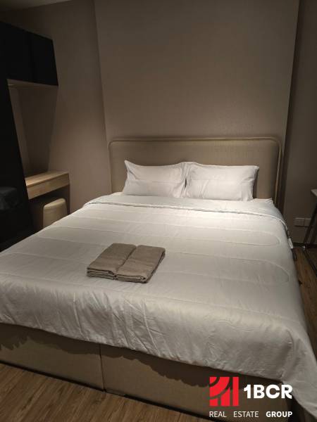 Schlafzimmer in einer Einzimmerwohnung mit einem großen Bett und einer Kommode.