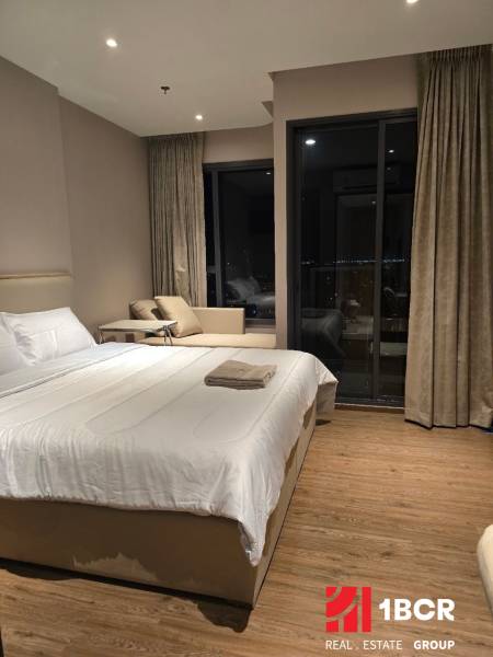 Unterkunft in einer Einzimmerwohnung mit Bett, Sofa und Balkon in gedämpften Farben.